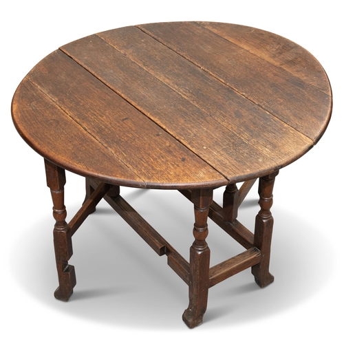 590 - AN 18TH CENTURY OAK GATELEG DINING TABLE, with D-shaped leaves, raised on a block and baluster stand... 