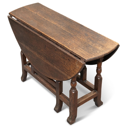 590 - AN 18TH CENTURY OAK GATELEG DINING TABLE, with D-shaped leaves, raised on a block and baluster stand... 