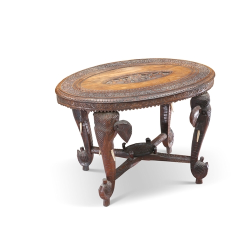 634 - AN ANGLO-INDIAN CARVED HARDWOOD OCCASIONAL TABLE, CIRCA 1900, the oval top carved with Buddha and el... 