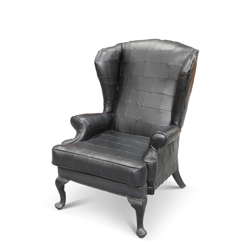 716 - A CONTEMPORARY BLACK LEATHER UPHOLSTERED WING-BACK ARMCHAIR, with cabriole legs terminating in pad f... 