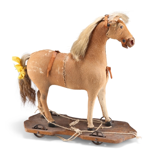 185 - A VICTORIAN PULL-ALONG TOY HORSE, the hide body raised on a wooden stand with metal wheels. 40cm hig... 