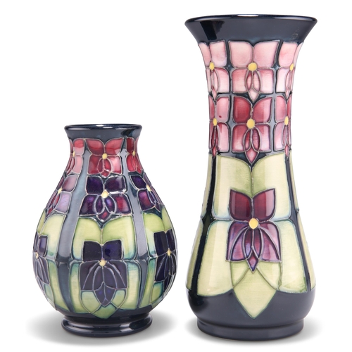 93 - TWO MOORCROFT VIOLET PATTERN TUBE LINED POTTERY VASES, designed by Sally Tuffin, one of trumpet form... 