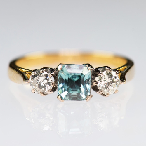 2120 - AN 18 CARAT GOLD BLUE ZIRCON AND DIAMOND THREE STONE RING an octagonal-cut blue zircon between round... 