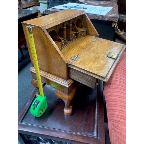 884 - AN 18TH CENTURY STYLE OAK MINIATURE BUREAU with fitted interior and drawer, raised on an integral st... 