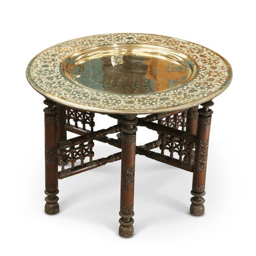 22 - A MOORISH CIRCULAR BRASS TRAY-TOP TABLE, CIRCA 1900 the turned folding stand with carved decoration.... 