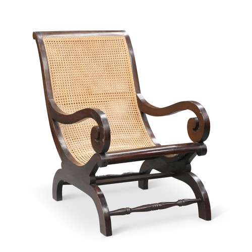 26 - A REPRODUCTION BERGÈRE PLANTATION CHAIR by LOMBOK, the curved teak frame with scroll arms and canewo... 