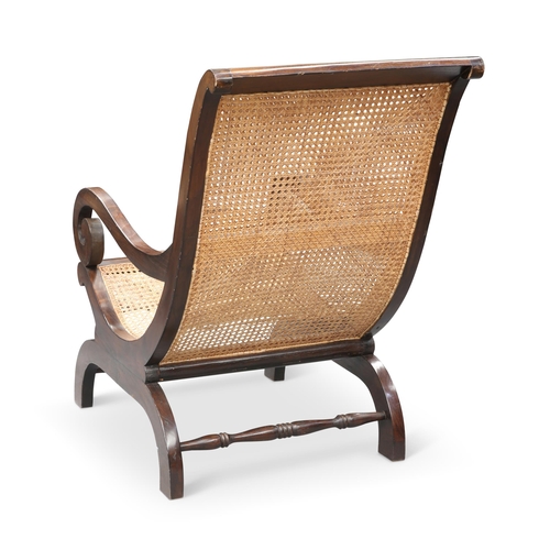 26 - A REPRODUCTION BERGÈRE PLANTATION CHAIR by LOMBOK, the curved teak frame with scroll arms and canewo... 