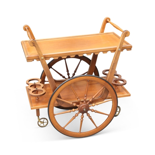 61 - A VINTAGE TEAK DRINKS TROLLEY with a pair of three-bottle holders, on large wheels with turned spoke... 