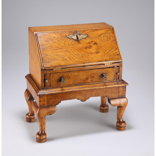 884 - AN 18TH CENTURY STYLE OAK MINIATURE BUREAU with fitted interior and drawer, raised on an integral st... 