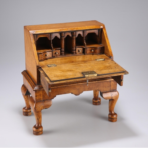 884 - AN 18TH CENTURY STYLE OAK MINIATURE BUREAU with fitted interior and drawer, raised on an integral st... 