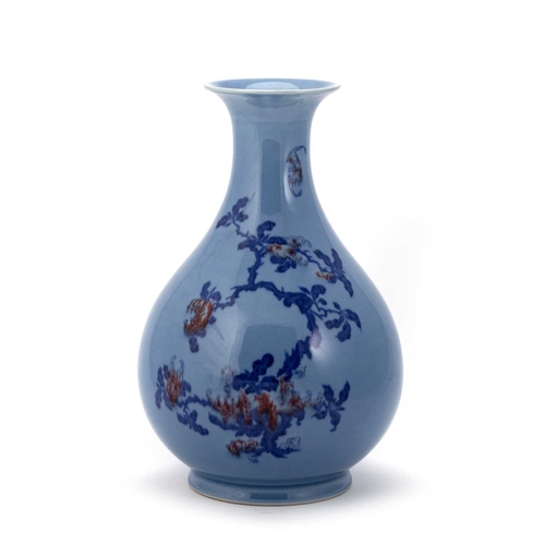 173 - AN UNDERGLAZE BLUE AND RED-DECORATED BLUE-GLAZED PEAR-SHAPED VASE painted with fruiting peach trees ... 