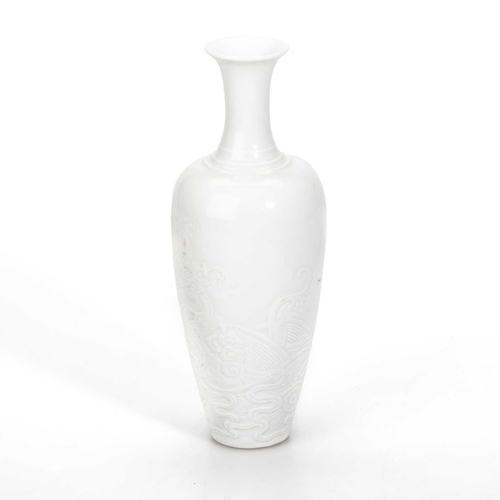 220 - A CHINESE WHITE-GLAZED PORCELAIN VASE the slender ovoid body moulded with a dragon. 18cm high