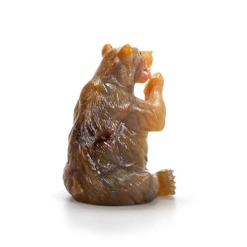 469A - A RUSSIAN AGATE MODEL OF A BEAR carved sitting and licking a raised paw, the open mouth displaying w... 