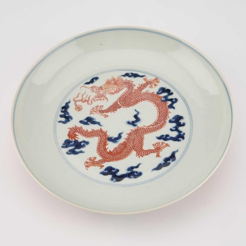 595 - A CHINESE UNDERGLAZE BLUE AND IRON-RED 'DRAGON' DISH circular with rounded sides, decorated with a f... 