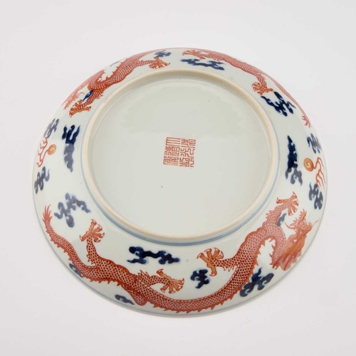 595 - A CHINESE UNDERGLAZE BLUE AND IRON-RED 'DRAGON' DISH circular with rounded sides, decorated with a f... 