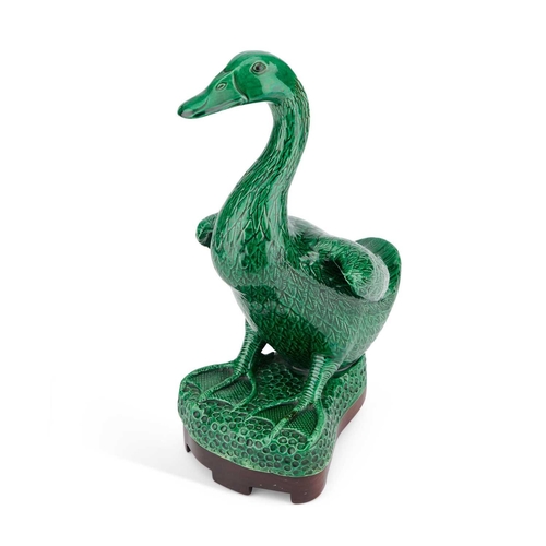 653 - A CHINESE GREEN-GLAZED MODEL OF A DUCK on a wooden stand. (2) 24.5cm high overall