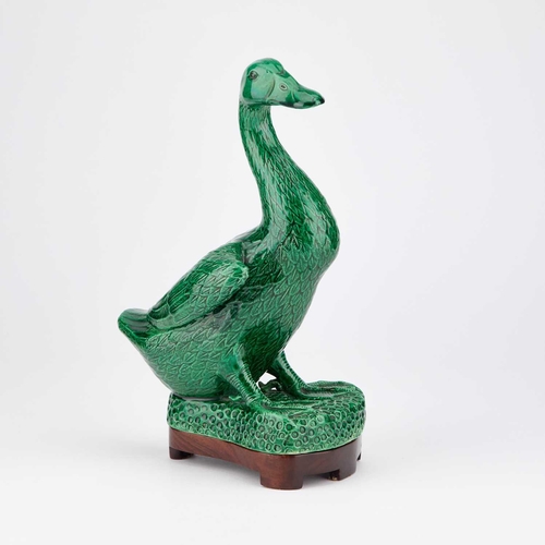 653 - A CHINESE GREEN-GLAZED MODEL OF A DUCK on a wooden stand. (2) 24.5cm high overall