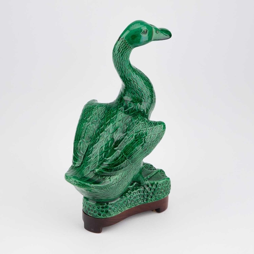 653 - A CHINESE GREEN-GLAZED MODEL OF A DUCK on a wooden stand. (2) 24.5cm high overall