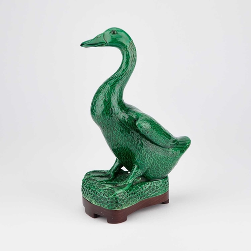 653 - A CHINESE GREEN-GLAZED MODEL OF A DUCK on a wooden stand. (2) 24.5cm high overall