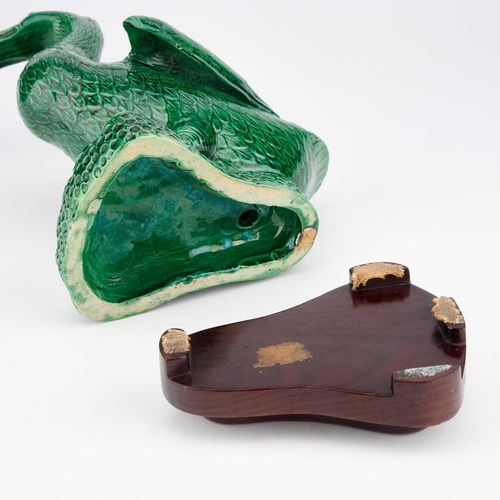 653 - A CHINESE GREEN-GLAZED MODEL OF A DUCK on a wooden stand. (2) 24.5cm high overall