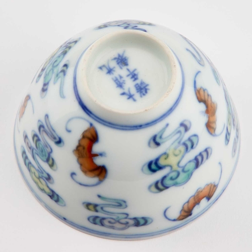 658 - A CHINESE DOUCAI TEA BOWL circular with rounded sides, decorated with bats and clouds, bears a six-c... 