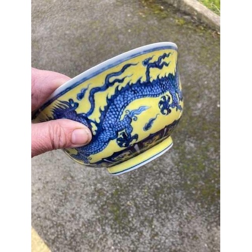 691 - A CHINESE MING STYLE YELLOW-GROUND BLUE AND WHITE 'DRAGON' BOWL painted with twin dragons chasing fl... 