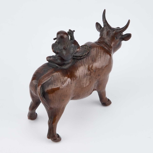 719 - A JAPANESE BRONZE MODEL OF A BULL atop his back a small boy sitting playing a flute. 13.5cm long... 