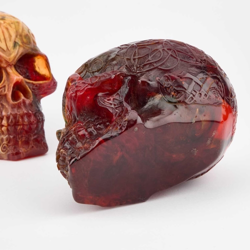 937 - THREE AMBER-COLOURED RESIN SKULLS each decorated all over with Celtic scrolls and motifs. (3) 12.5cm... 