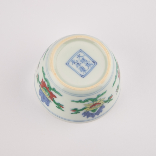 103 - A CHINESE DOUCAI CUP decorated with flowers, bears an underglaze blue six-character mark in a double... 