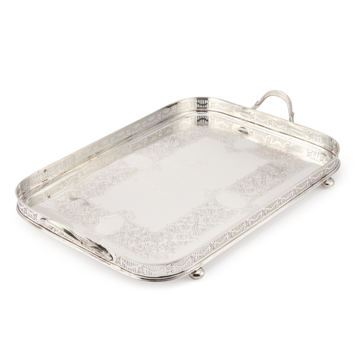 188 - A LARGE LATE VICTORIAN SILVER-PLATED GALLERIED TRAY with twin handles and bun feet. 69cm long across... 