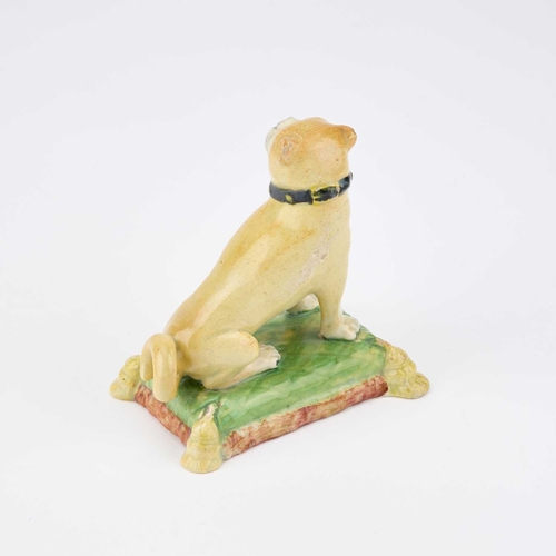 47 - A 19TH CENTURY POTTERY MODEL OF A SEATED PUG the dog on its haunches, on a green cushion with a tass... 