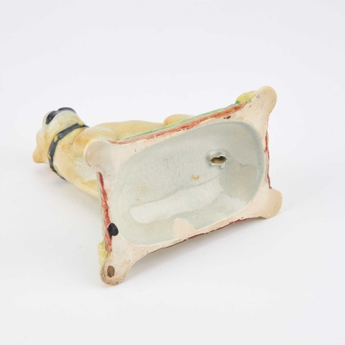 47 - A 19TH CENTURY POTTERY MODEL OF A SEATED PUG the dog on its haunches, on a green cushion with a tass... 