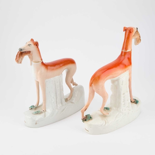 63 - A NEAR PAIR OF VICTORIAN STAFFORDSHIRE POTTERY MODELS OF GREYHOUNDS together with a pair of pottery ... 