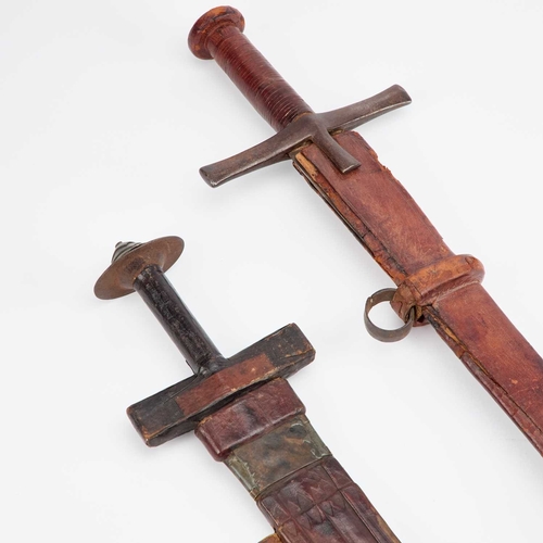 7 - TWO TAKOUBA WITH SCABBARDS each with a tapering blade, one with a pair of crescent moons to either s... 