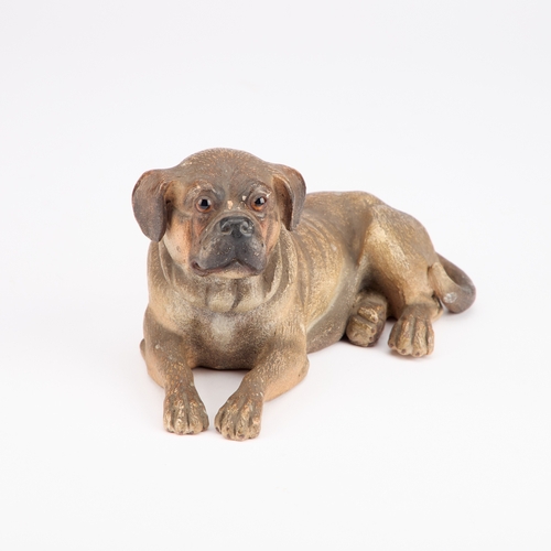 38 - AN AUSTRIAN PAINTED TERRACOTTA MODEL OF A RECUMBENT DOG late 19th Century. 19.5cm long