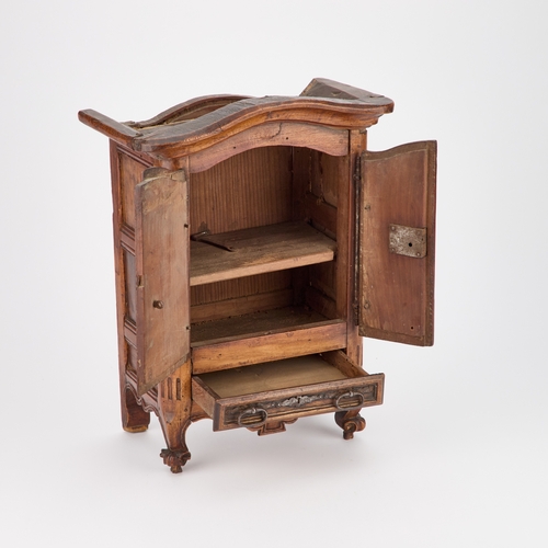 829 - AN ANTIQUE CARVED MINIATURE ARMOIRE with carved initials on the top, fitted with a pair of doors and... 