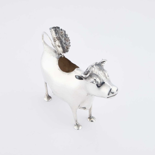 423 - AN EARLY GEORGE III SILVER COW CREAMER by John Schuppe, London 1760, modelled as a cow, standing on ... 