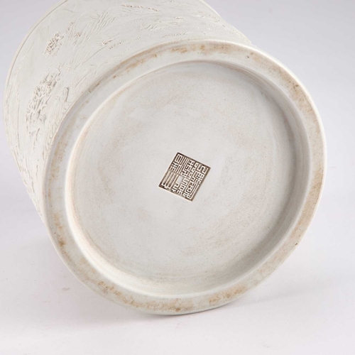 86 - A CHINESE CARVED BISCUIT PORCELAIN BRUSH POT cylindrical, decorated with a battle scene and fortress... 