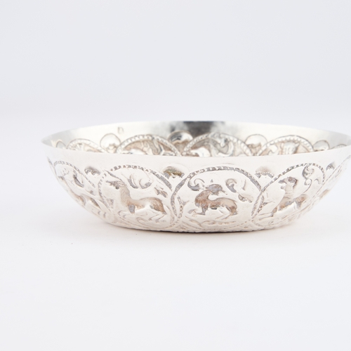 393 - A GREEK SILVER DISH circular form, heavily chased with animals within roundels. 12.2cm diameter, 2.6... 