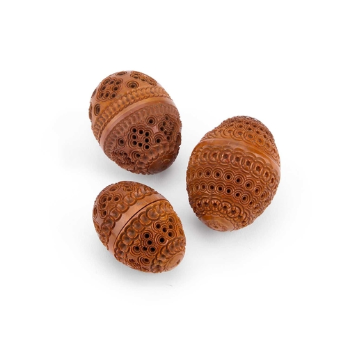 124 - THREE PIERCED AND CARVED COQUILLA NUTS comprising two flea traps and a shaker/ pepper, each egg-shap... 