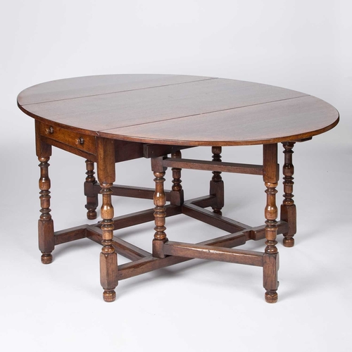 1309 - A LARGE TITCHMARSH & GOODWIN OAK GATELEG DINING TABLE with rounded leaves, raised on block and balus... 