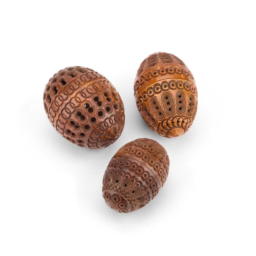 287 - THREE PIERCED AND CARVED COQUILLA NUTS each egg-shaped. (3) Largest 6.5cm high