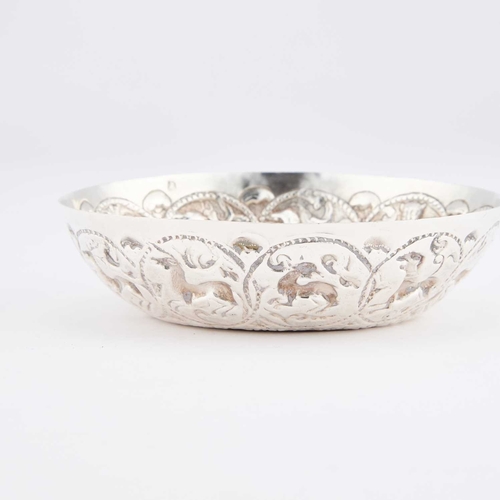 393 - A GREEK SILVER DISH circular form, heavily chased with animals within roundels. 12.2cm diameter, 2.6... 