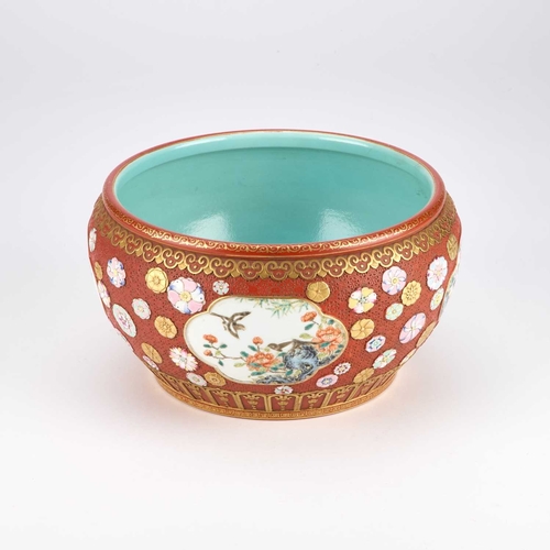 892 - A CHINESE FAMILLE ROSE ENAMELLED CORAL-RED GROUND JARDINIÃRE the rounded sides reserved with four l... 