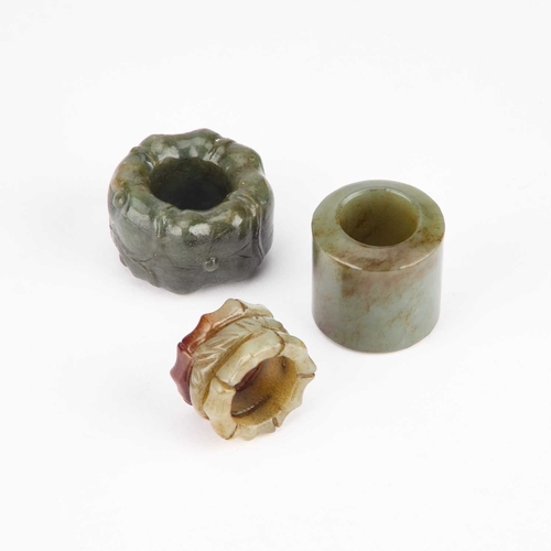 952 - THREE CHINESE JADE THUMB RINGS one pierced and carved as bamboo, another decorated with flowerheads,... 