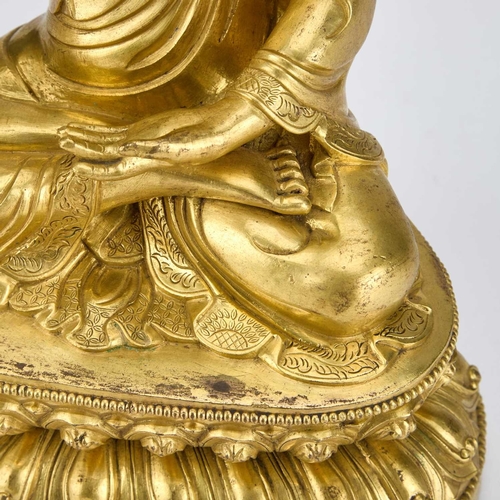 979 - A GILT-BRONZE SEATED FIGURE OF BUDDHA 18TH CENTURY OR EARLIER wearing a voluminous, well-defined san... 