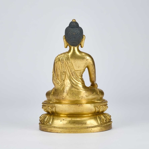 979 - A GILT-BRONZE SEATED FIGURE OF BUDDHA 18TH CENTURY OR EARLIER wearing a voluminous, well-defined san... 