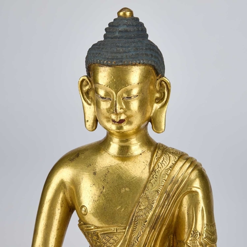 979 - A GILT-BRONZE SEATED FIGURE OF BUDDHA 18TH CENTURY OR EARLIER wearing a voluminous, well-defined san... 