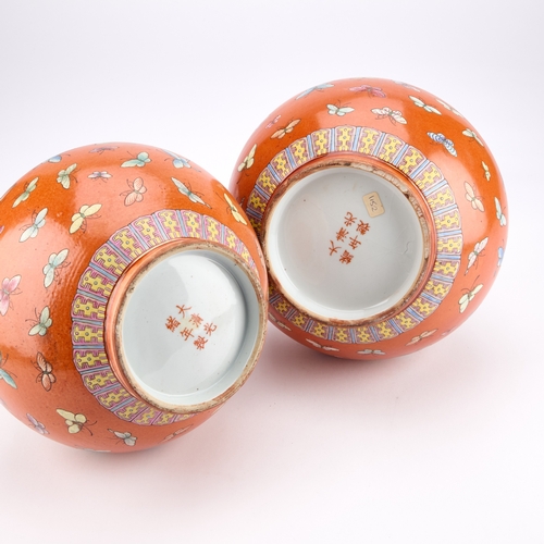 131 - A PAIR OF CHINESE FAMILLE ROSE 'BUTTERFLY' VASES each decorated on a vibrant coral ground, enamelled... 