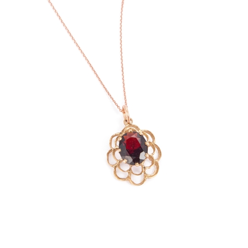 634 - A 9 CARAT GOLD GARNET PENDANT ON A ROSE GOLD CHAIN an oval-cut garnet within a fancy pierced frame, ... 